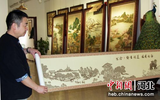 图为马振领为参观者展示部分剪纸长卷《渤海明珠 运河古郡 沧州》。刘广和 摄